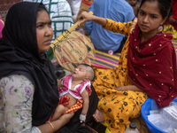 Women are holding their children while standing outside the Dhaka Shishu (Children) Hospital after a fire broke out inside the intensive car...