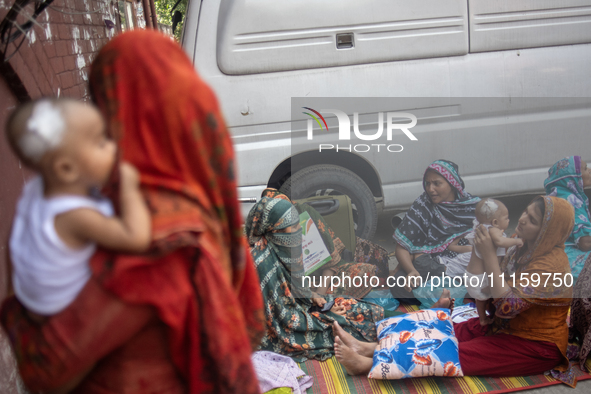 Women are holding their children while standing outside the Dhaka Shishu (Children) Hospital after a fire broke out inside the intensive car...