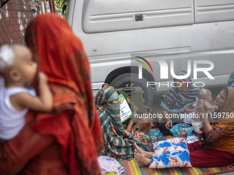 Women are holding their children while standing outside the Dhaka Shishu (Children) Hospital after a fire broke out inside the intensive car...