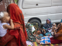 Women are holding their children while standing outside the Dhaka Shishu (Children) Hospital after a fire broke out inside the intensive car...