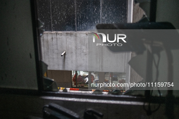 A man is sitting inside a hospital ward, looking through broken window glass at the aftermath of a fire that broke out in the intensive care...