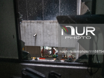 A man is sitting inside a hospital ward, looking through broken window glass at the aftermath of a fire that broke out in the intensive care...