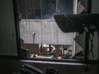 A man is sitting inside a hospital ward, looking through broken window glass at the aftermath of a fire that broke out in the intensive care...