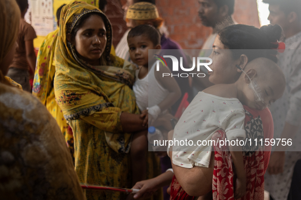 Women are holding their children while standing outside the Dhaka Shishu (Children) Hospital after a fire broke out inside the intensive car...