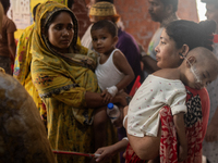 Women are holding their children while standing outside the Dhaka Shishu (Children) Hospital after a fire broke out inside the intensive car...