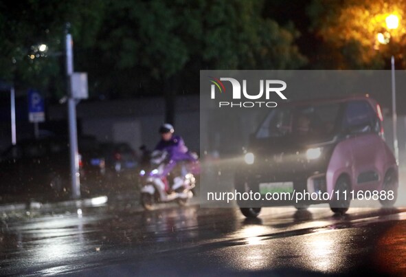 People are riding along a waterlogged road in Chang'an town, Rongan County, Liuzhou City, Guangxi Zhuang Autonomous Region, South China, on...