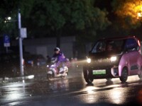 People are riding along a waterlogged road in Chang'an town, Rongan County, Liuzhou City, Guangxi Zhuang Autonomous Region, South China, on...