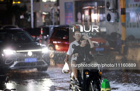 People are riding along a waterlogged road in Chang'an town, Rongan County, Liuzhou City, Guangxi Zhuang Autonomous Region, South China, on...