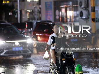 People are riding along a waterlogged road in Chang'an town, Rongan County, Liuzhou City, Guangxi Zhuang Autonomous Region, South China, on...