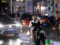 People are riding along a waterlogged road in Chang'an town, Rongan County, Liuzhou City, Guangxi Zhuang Autonomous Region, South China, on...