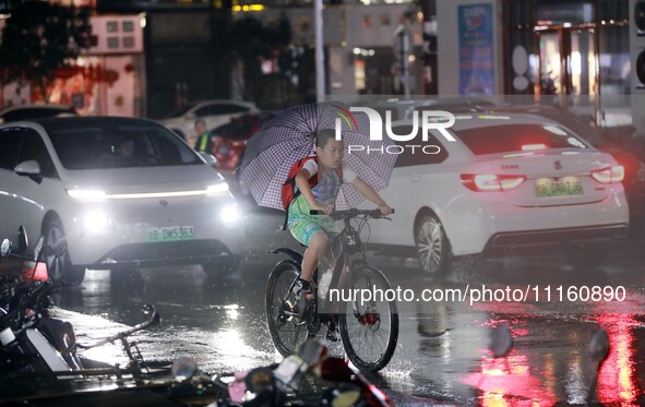 People are riding along a waterlogged road in Chang'an town, Rongan County, Liuzhou City, Guangxi Zhuang Autonomous Region, South China, on...