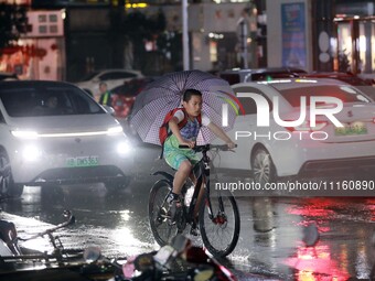 People are riding along a waterlogged road in Chang'an town, Rongan County, Liuzhou City, Guangxi Zhuang Autonomous Region, South China, on...