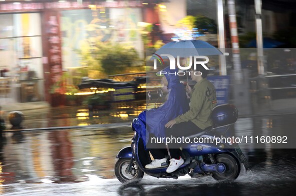 People are riding along a waterlogged road in Chang'an town, Rongan County, Liuzhou City, Guangxi Zhuang Autonomous Region, South China, on...