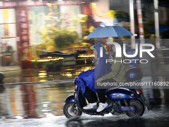 People are riding along a waterlogged road in Chang'an town, Rongan County, Liuzhou City, Guangxi Zhuang Autonomous Region, South China, on...