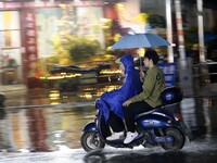 People are riding along a waterlogged road in Chang'an town, Rongan County, Liuzhou City, Guangxi Zhuang Autonomous Region, South China, on...