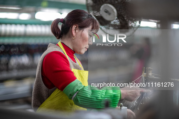 A worker is drawing silk at a mulberry silk processing workshop in Xinghua, China, on April 20, 2024. 