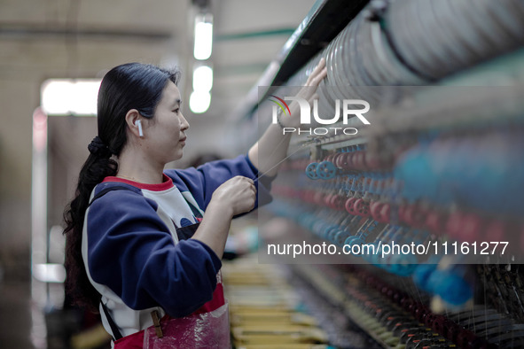 A worker is drawing silk at a mulberry silk processing workshop in Xinghua, China, on April 20, 2024. 