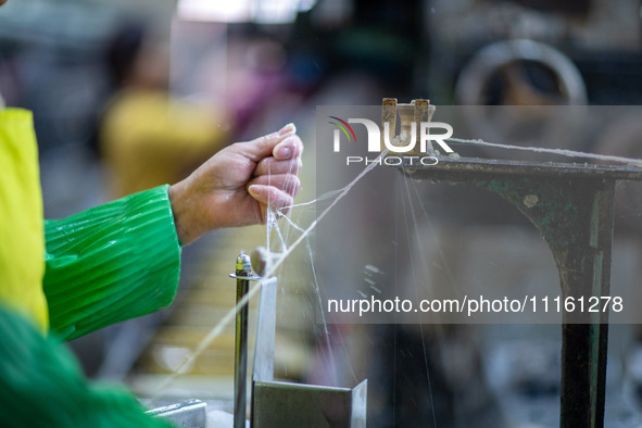 A worker is drawing silk at a mulberry silk processing workshop in Xinghua, China, on April 20, 2024. 