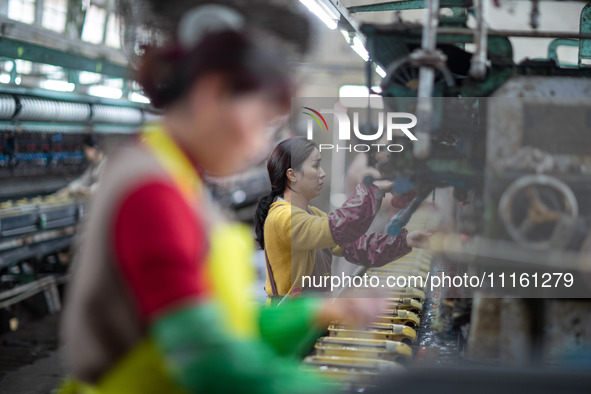 A worker is drawing silk at a mulberry silk processing workshop in Xinghua, China, on April 20, 2024. 