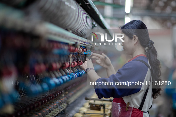 A worker is drawing silk at a mulberry silk processing workshop in Xinghua, China, on April 20, 2024. 