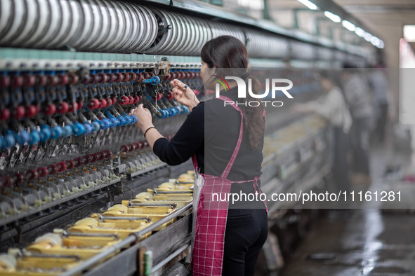 A worker is drawing silk at a mulberry silk processing workshop in Xinghua, China, on April 20, 2024. 