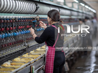 A worker is drawing silk at a mulberry silk processing workshop in Xinghua, China, on April 20, 2024. (