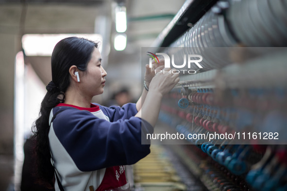 A worker is drawing silk at a mulberry silk processing workshop in Xinghua, China, on April 20, 2024. 