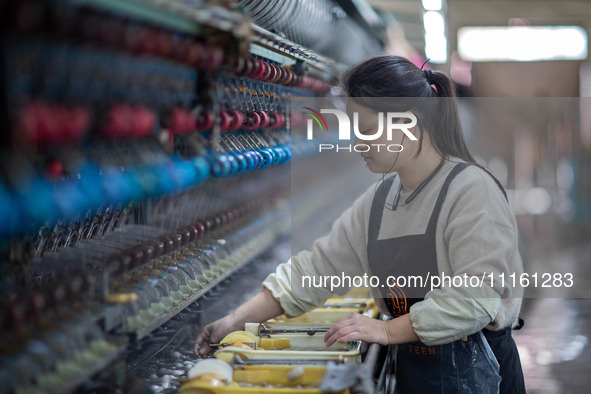 A worker is drawing silk at a mulberry silk processing workshop in Xinghua, China, on April 20, 2024. 