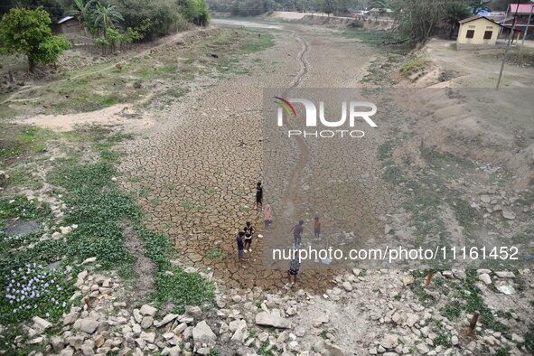 Children are playing near the dry bed of a lake in Kathiatoli town, Nagaon District, Assam, India, on April 20, 2024. 