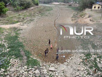 Children are playing near the dry bed of a lake in Kathiatoli town, Nagaon District, Assam, India, on April 20, 2024. (