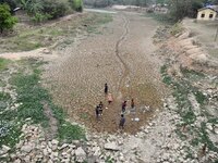 Children are playing near the dry bed of a lake in Kathiatoli town, Nagaon District, Assam, India, on April 20, 2024. (