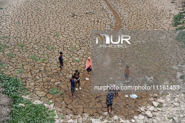 Children are playing near the dry bed of a lake in Kathiatoli town, Nagaon District, Assam, India, on April 20, 2024. 