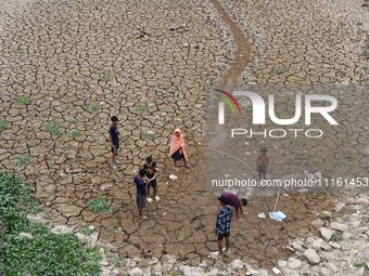 Children are playing near the dry bed of a lake in Kathiatoli town, Nagaon District, Assam, India, on April 20, 2024. (