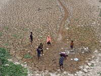 Children are playing near the dry bed of a lake in Kathiatoli town, Nagaon District, Assam, India, on April 20, 2024. (