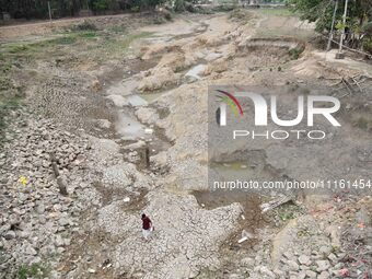 People are walking across the dry bed of a lake in Kathiatoli town, Nagaon District, Assam, India, on April 20, 2024. (