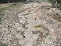 People are walking across the dry bed of a lake in Kathiatoli town, Nagaon District, Assam, India, on April 20, 2024. (