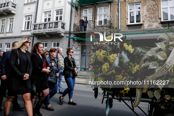 Family and friends walk in a funeral procession as residents on a balcony send they respects during funeral of Damian Sobol, a volunteer for...