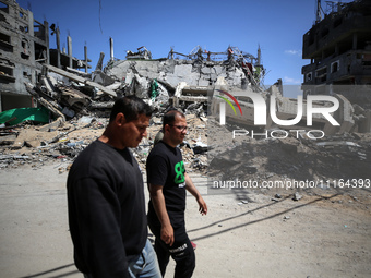 Palestinians are walking past a destroyed mosque in the city of Nuseirat in the central Gaza Strip on April 21, 2024, amid ongoing battles b...