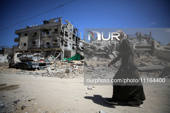 A Palestinian woman is walking past a destroyed mosque in Nuseirat, central Gaza Strip, on April 21, 2024, amid ongoing battles between Isra...