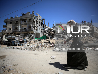 A Palestinian woman is walking past a destroyed mosque in Nuseirat, central Gaza Strip, on April 21, 2024, amid ongoing battles between Isra...