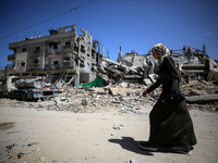 A Palestinian woman is walking past a destroyed mosque in Nuseirat, central Gaza Strip, on April 21, 2024, amid ongoing battles between Isra...