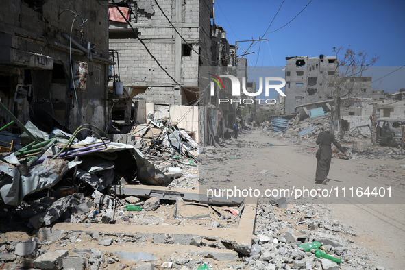 A Palestinian woman is walking past a destroyed building in Nuseirat, Gaza Strip, on April 21, 2024, amid ongoing battles between Israel and...