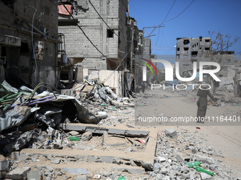 A Palestinian woman is walking past a destroyed building in Nuseirat, Gaza Strip, on April 21, 2024, amid ongoing battles between Israel and...