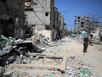 A Palestinian woman is walking past a destroyed building in Nuseirat, Gaza Strip, on April 21, 2024, amid ongoing battles between Israel and...