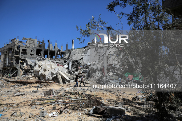 Palestinians are walking past a destroyed building in Nuseirat, Gaza Strip, on April 21, 2024, amid ongoing battles between Israel and the m...