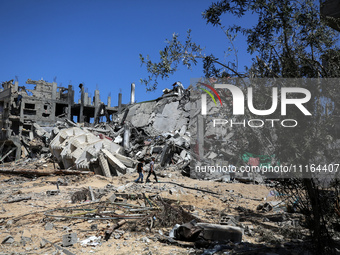 Palestinians are walking past a destroyed building in Nuseirat, Gaza Strip, on April 21, 2024, amid ongoing battles between Israel and the m...