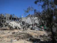 Palestinians are walking past a destroyed building in Nuseirat, Gaza Strip, on April 21, 2024, amid ongoing battles between Israel and the m...