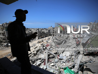 A Palestinian man is standing past a destroyed building in the city of Nuseirat in the central Gaza Strip on April 21, 2024, amid ongoing ba...