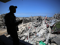 A Palestinian man is standing past a destroyed building in the city of Nuseirat in the central Gaza Strip on April 21, 2024, amid ongoing ba...