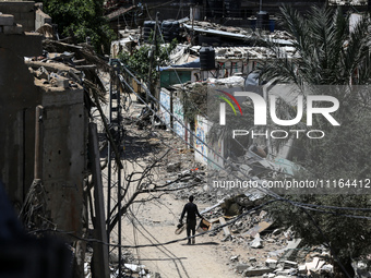 A Palestinian man is walking past a destroyed building in Nuseirat, Gaza Strip, on April 21, 2024, amid ongoing battles between Israel and t...